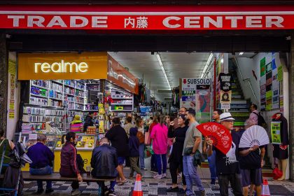 Consumidores circulam por um centro comercial movimentado, entre bancas e lojas.
