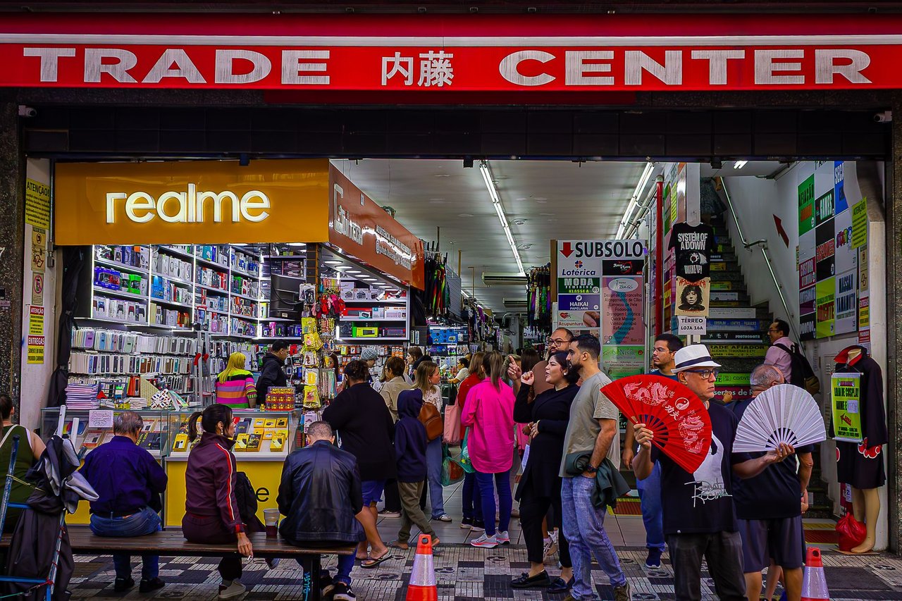 Consumidores circulam por um centro comercial movimentado, entre bancas e lojas.