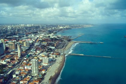 Vista aérea da orla de Fortaleza, com a faixa de praia, o mar e a área urbana da cidade